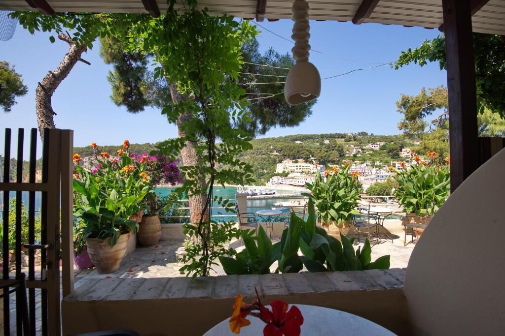 Una terraza con plantas en macetas, vistas a un pueblo costero y cielo despejado.