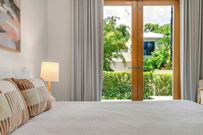 Camera da letto con un letto, una lampada e vista su un giardino attraverso una porta di vetro.
