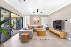 Un salon moderne comprenant un canapé, une table basse, un téléviseur et un ventilateur de plafond.