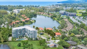 Un complexe hôtelier doté d’un lac central, entouré d’une végétation luxuriante et de bâtiments résidentiels.