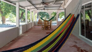 A covered outdoor area with a hammock, chairs, and a table.
