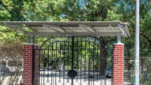 A gated entrance with a metal gate and a brick pillar.