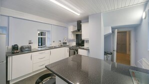 A modern kitchen with white cabinets, a granite countertop, and a black chair. - Constancevilla B9 | Grampian Lettings Ltd (Bucksburn)
