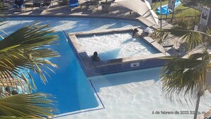 Un área de piscina con hidromasaje, sillas de descanso y palmeras.