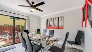 A modern dining area with a glass table, black chairs, and a ceiling fan. - Spacious 4BR Miami Townhome | Communal Pool (Miami)