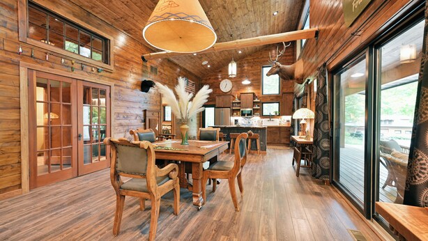 Un intérieur en bois comprenant un coin repas, une cuisine et de grandes fenêtres.