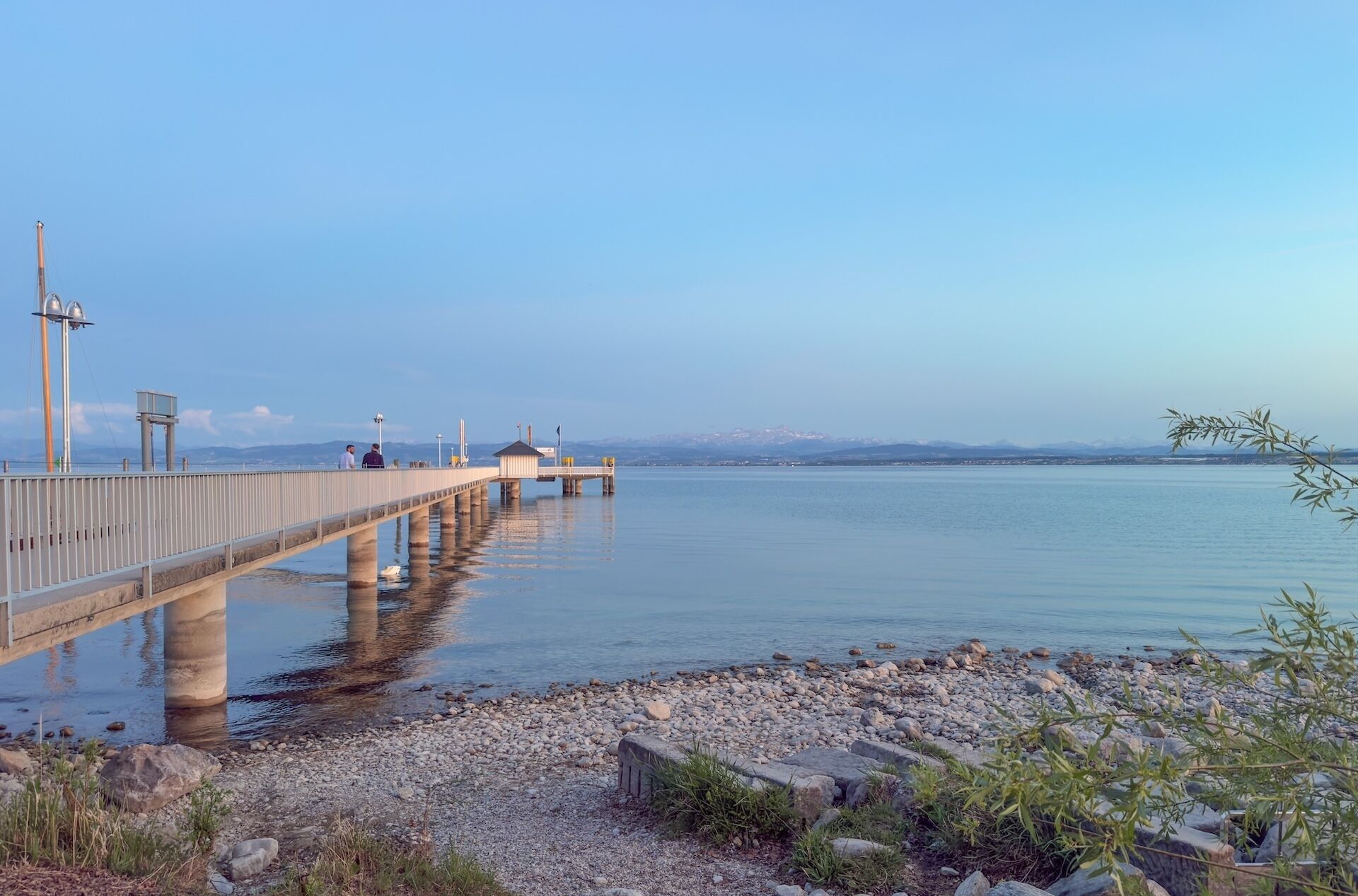 A pier extending into calm water with a clear sky.