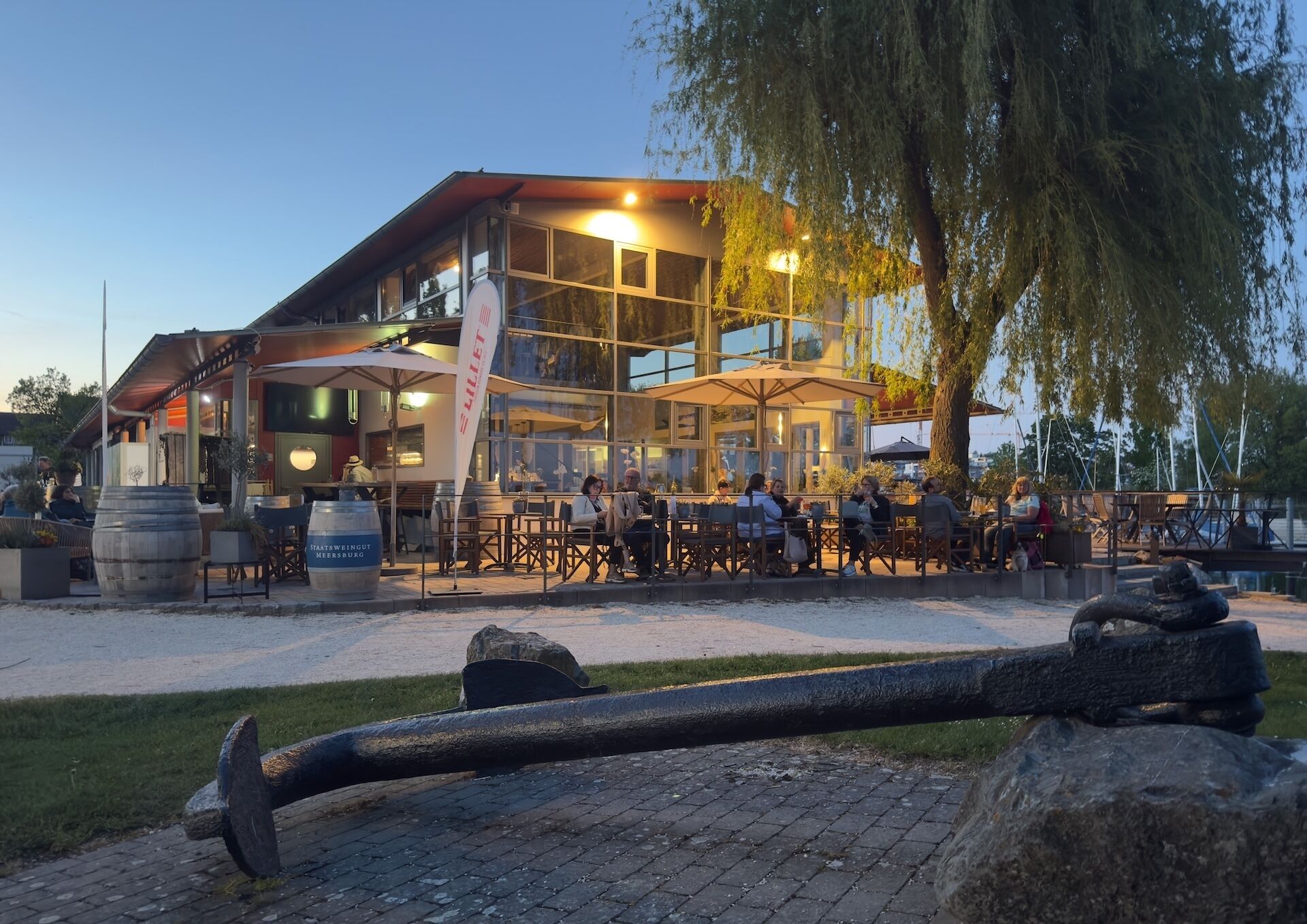 Un restaurante con terraza, fachada de vidrio amplia y un letrero que dice 'Staatsweinigt Meersburg'.