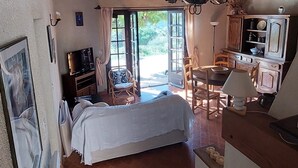 A rustic room with a bed, a dining table, and a kitchen area.