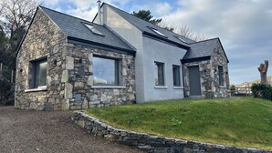 Ein Haus aus Stein mit modernem Design, das ein geneigtes Dach und große Fenster aufweist.