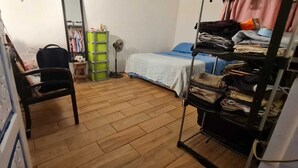 Un dormitorio con cama, una silla, armario y espejo.