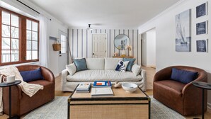 Ein Wohnzimmer mit einer Couch, zwei Sesseln, einem Couchtisch und einem Bücherregal.
