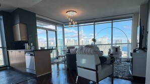 Un salón moderno con un ventanal grande, un sofá, una mesita de centro y vistas a un paisaje urbano.