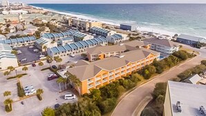 Oversigtsbillede af et kysthotel med flere bygninger, en parkeringsplads og en strand i baggrunden.