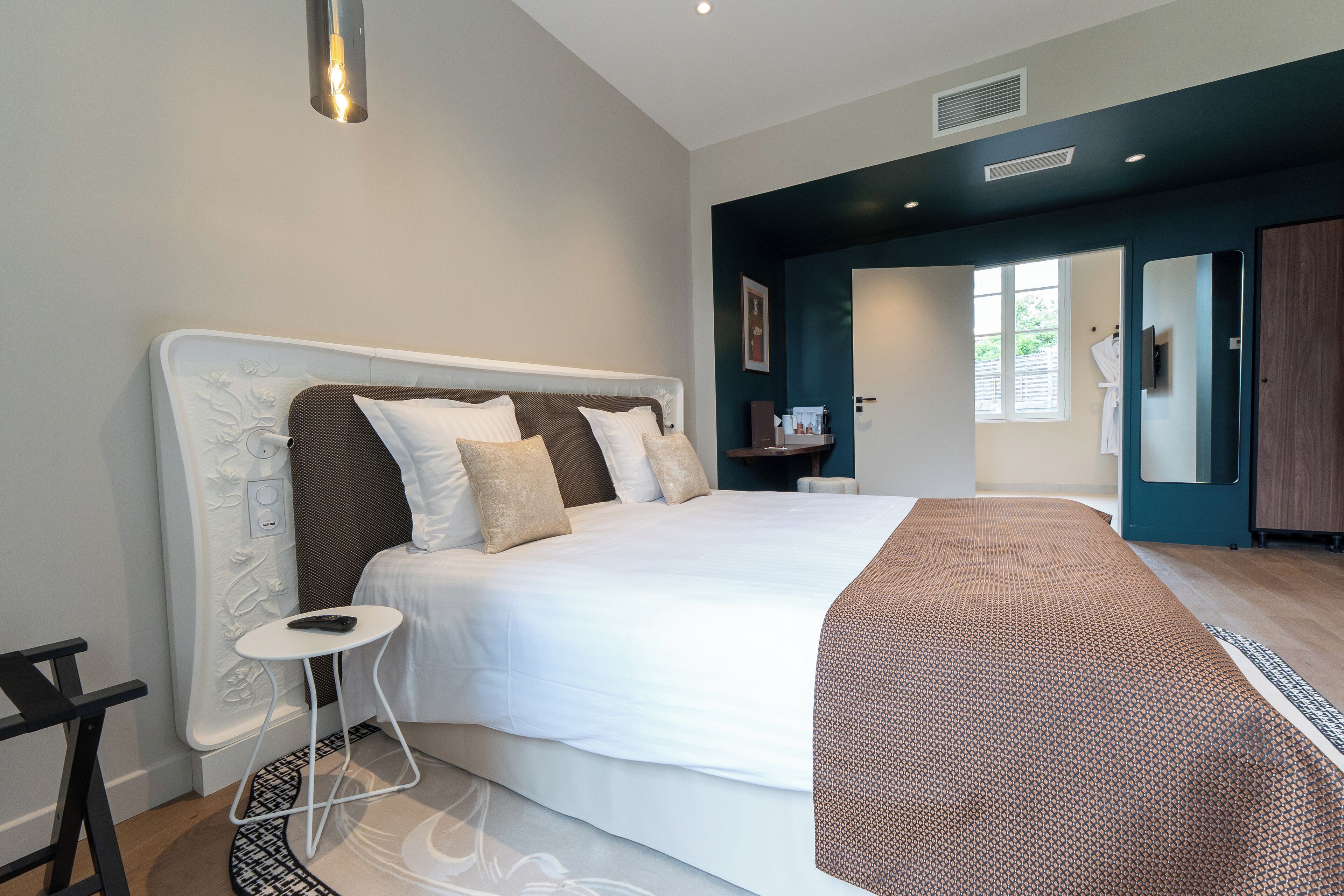 A modern bedroom with a large bed, a bedside table, and a built-in wardrobe.
