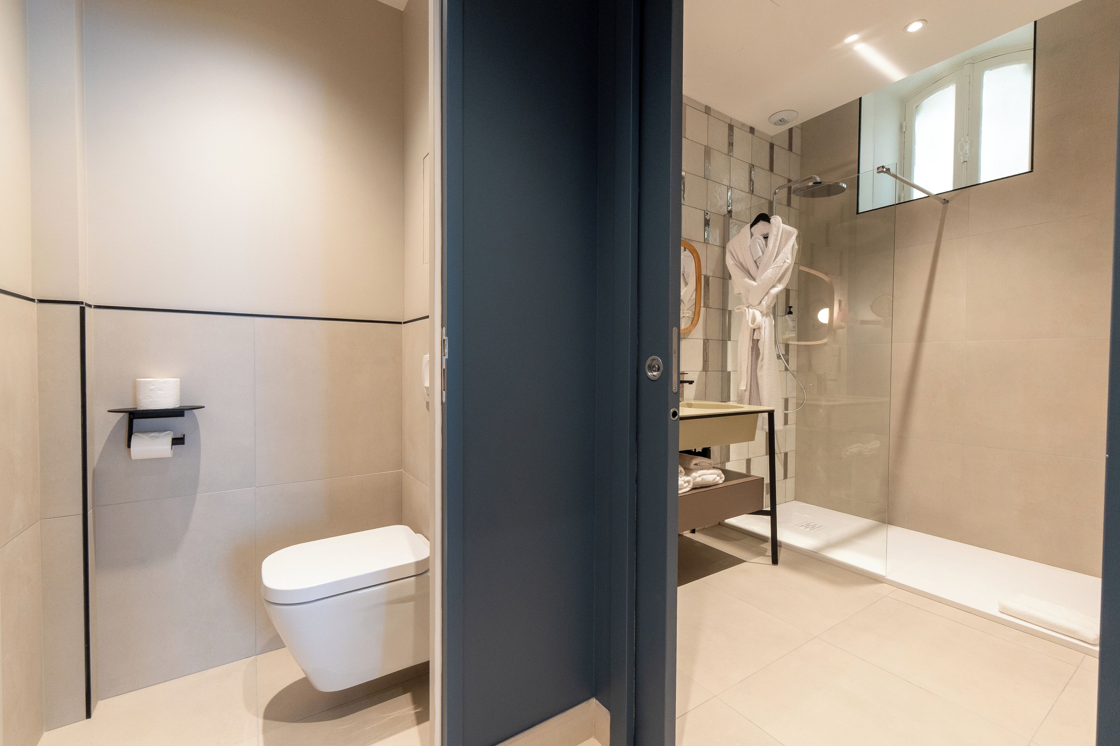 A modern bathroom with a toilet, a shower, and a glass-enclosed walk-in shower.