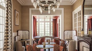 Un comedor con candelabro, mesa redonda y sillas tapizadas en rojo.