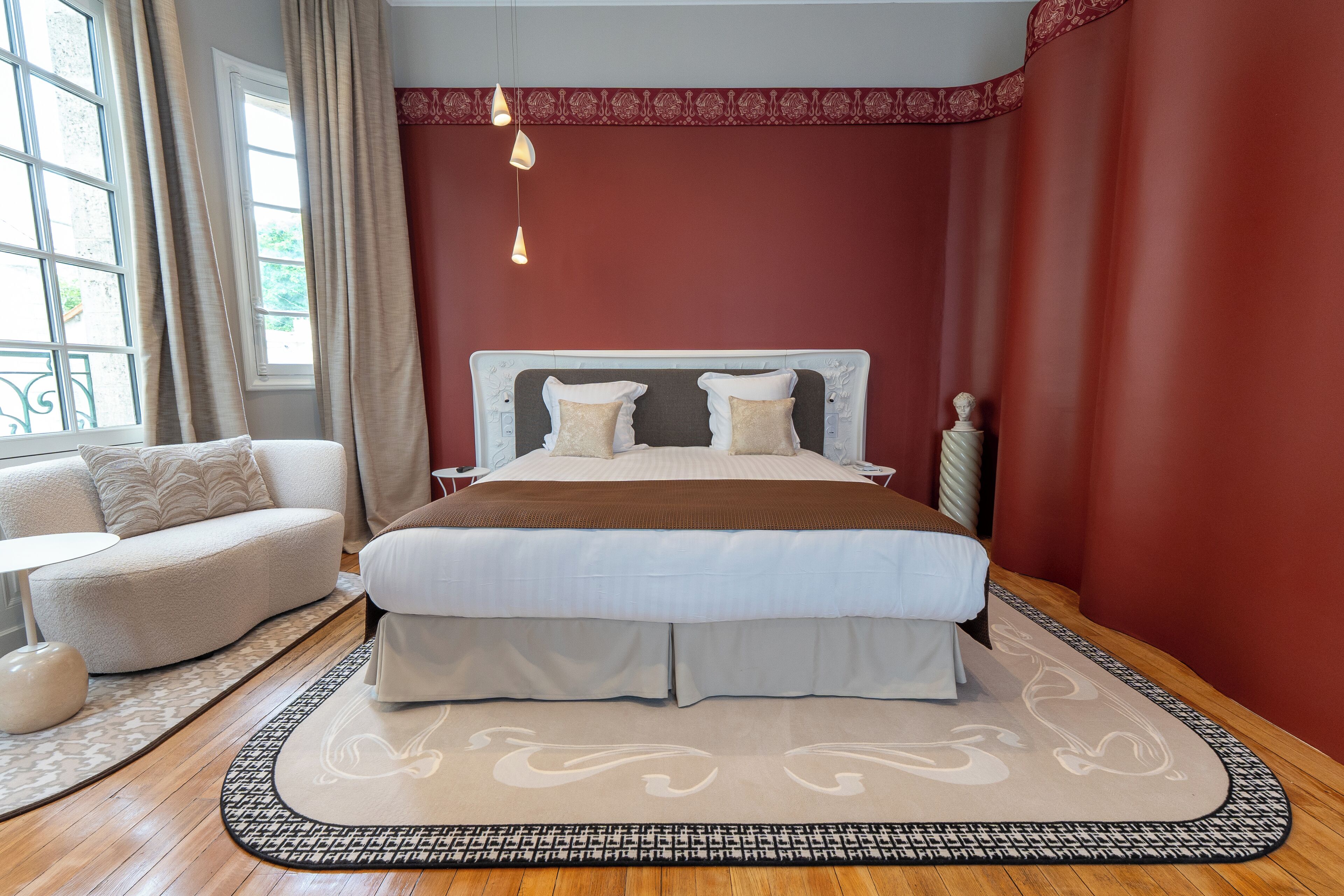 Une chambre à coucher avec un grand lit, un canapé, un tapis à motifs et une fenêtre avec des rideaux.