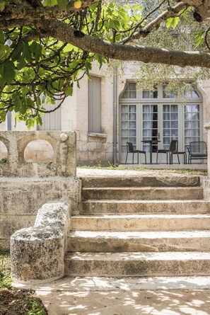 A stone staircase leading to a building with large windows and a seating area with chairs. - Hôtel des Arts (Angoulême)