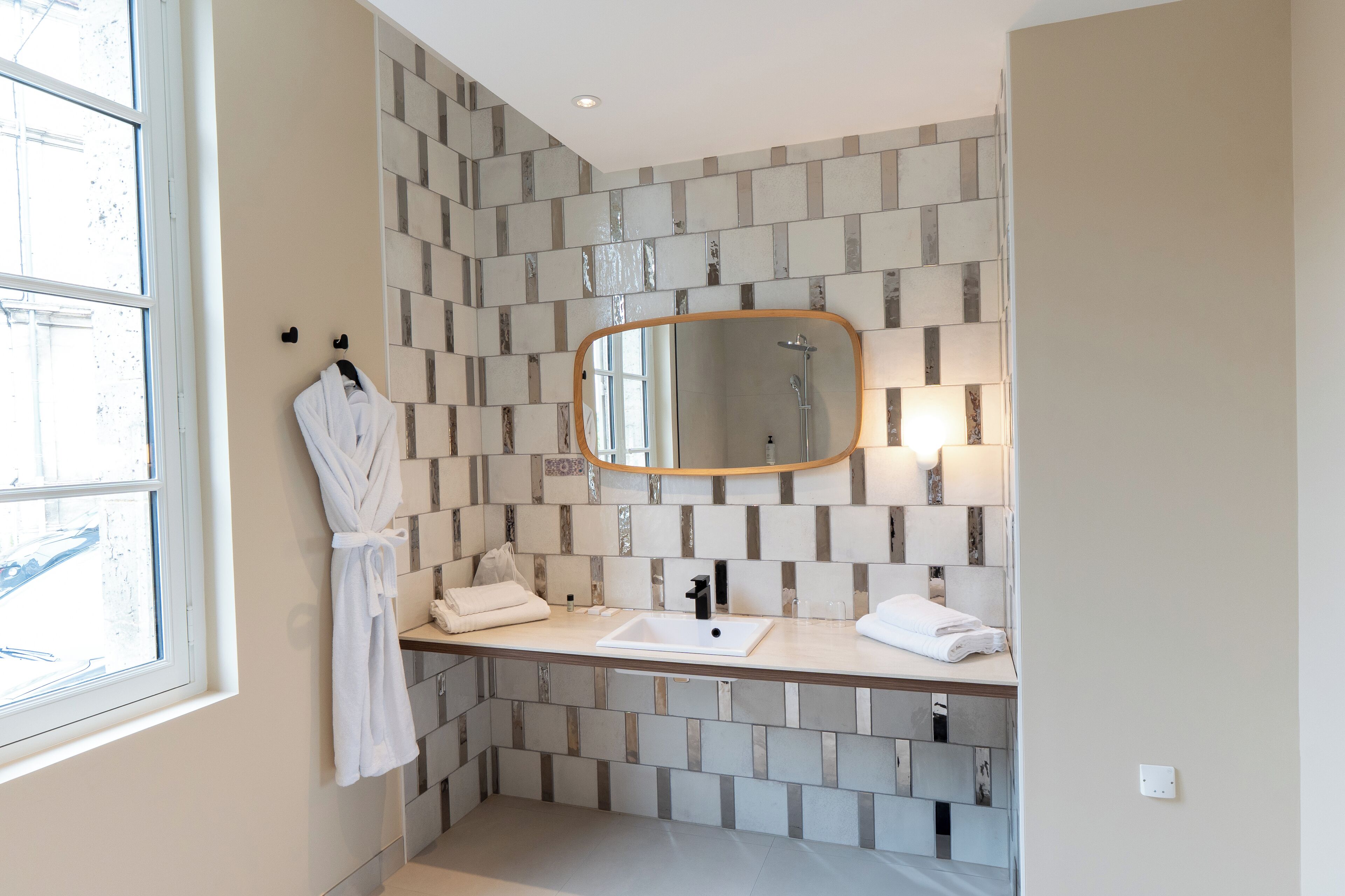 A bathroom with a large mirror, a sink, and a window.