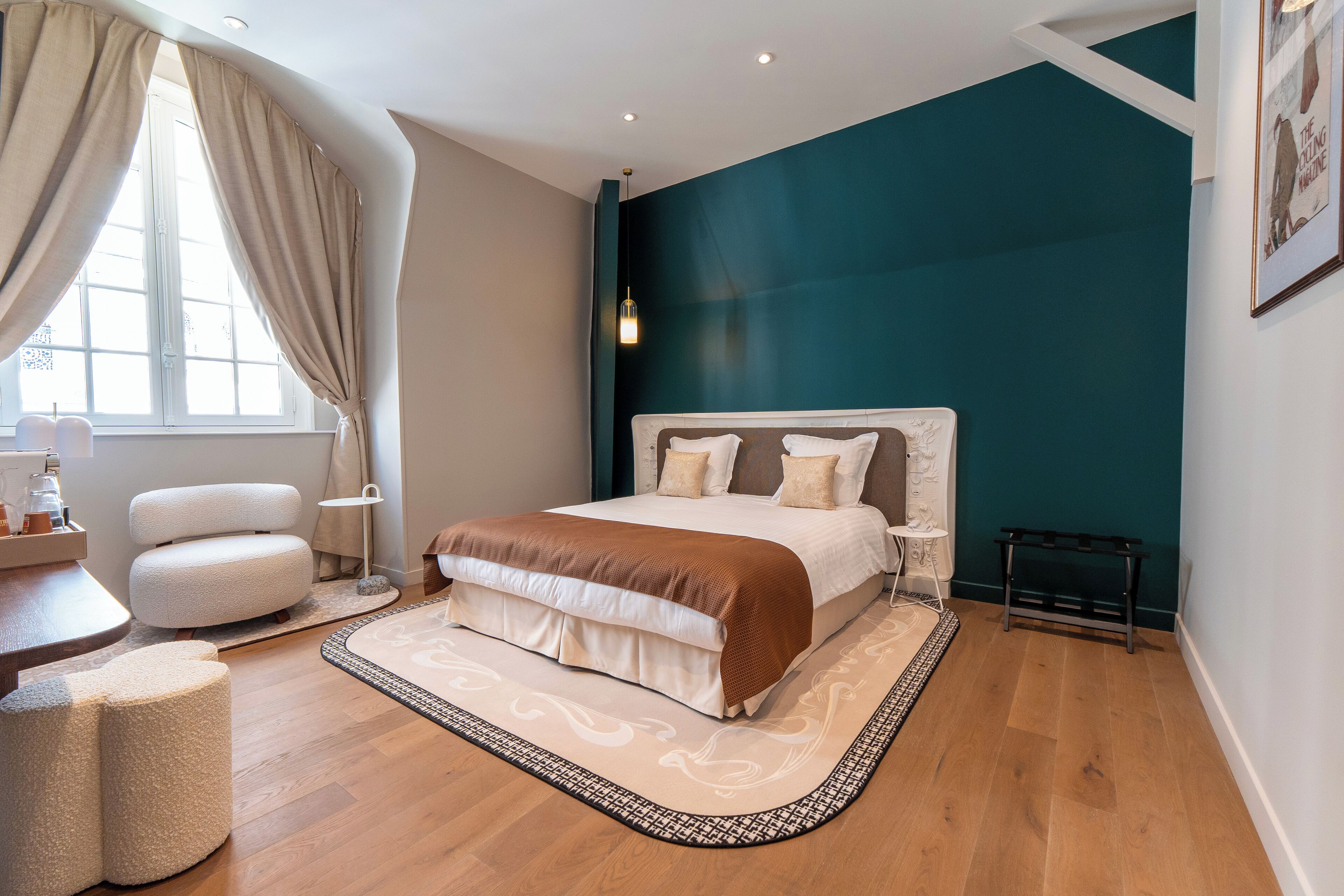 Une chambre avec un grand lit, une table de chevet, une chaise et une fenêtre avec des rideaux.