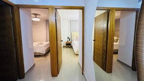 A hallway with two bedrooms, each with a bed, bedside table, and lamp.