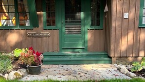 A building with a green door and windows, a sign reading "Still Meadow", and a stone pathway leading to the entrance. - Two charming cottages, a quiet ocean cove, a serene forest with private trails (Phippsburg)