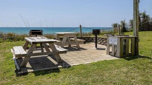 Area picnic con panche e tavoli di legno, una postazione barbecue e un cartello che indica l'uso esclusivo del barbecue.
