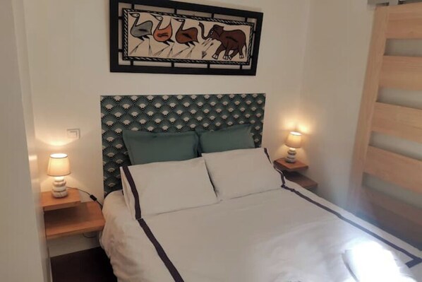 A neatly made bed with a patterned headboard, two bedside lamps, and a framed artwork above the bed.
