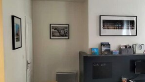 Zona de recepción de hotel con mostrador, cuadros en la pared e indicación de disponibilidad de Wi-Fi.