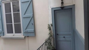 Fachada de edificio con una ventana y una puerta, ambas con contraventanas azules.