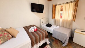 A bedroom with two beds, a television mounted on the wall, and a window with curtains. - Pousada Princesa da Serra (Santana do Riacho)
