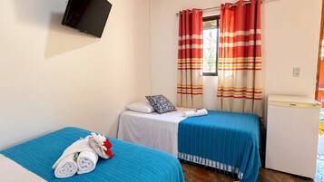 Een hotelkamer met twee bedden, een aan de muur bevestigde televisie, een raam met gestreepte gordijnen en een kleine koelkast.