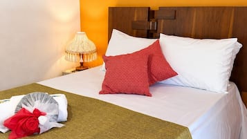 A hotel room with a bed, a nightstand with a lamp, and a wall decoration.
