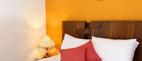 A hotel room with a bed, a nightstand with a lamp, and a wall decoration.