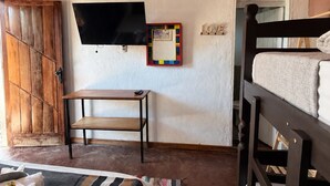 A room with a bunk bed, a desk with a chair, a television mounted on the wall, and a wooden wardrobe. - Pousada Princesa da Serra (Santana do Riacho)