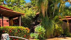 A swimming pool with a stone wall, surrounded by tropical plants and a wooden pergola. - Pousada Princesa da Serra (Santana do Riacho)
