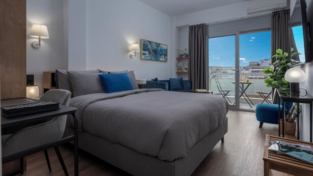 A modern hotel room with a large bed, a desk, a balcony with a view, and a TV.