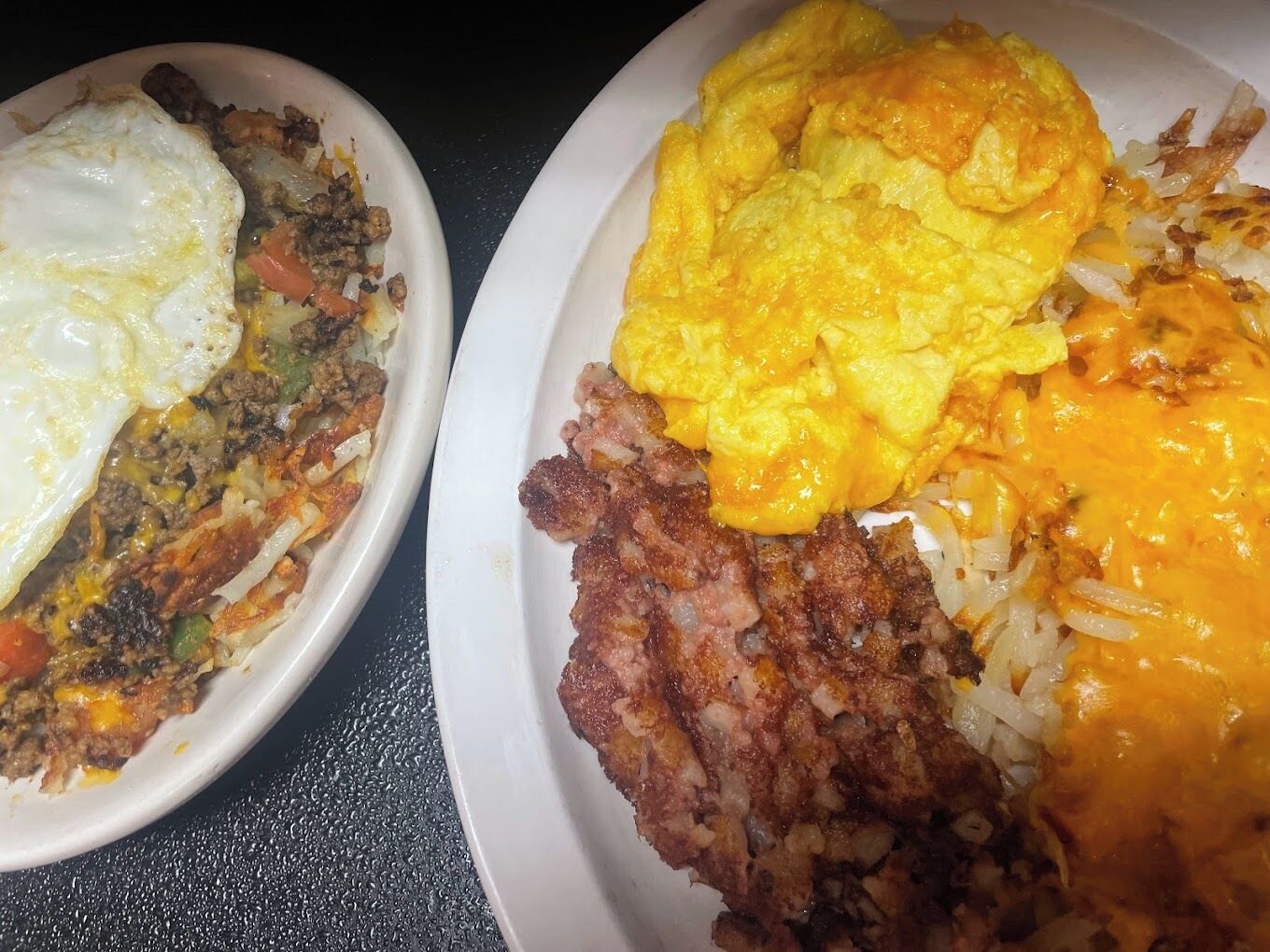 Two plates of food with scrambled eggs, fried meat, and rice.