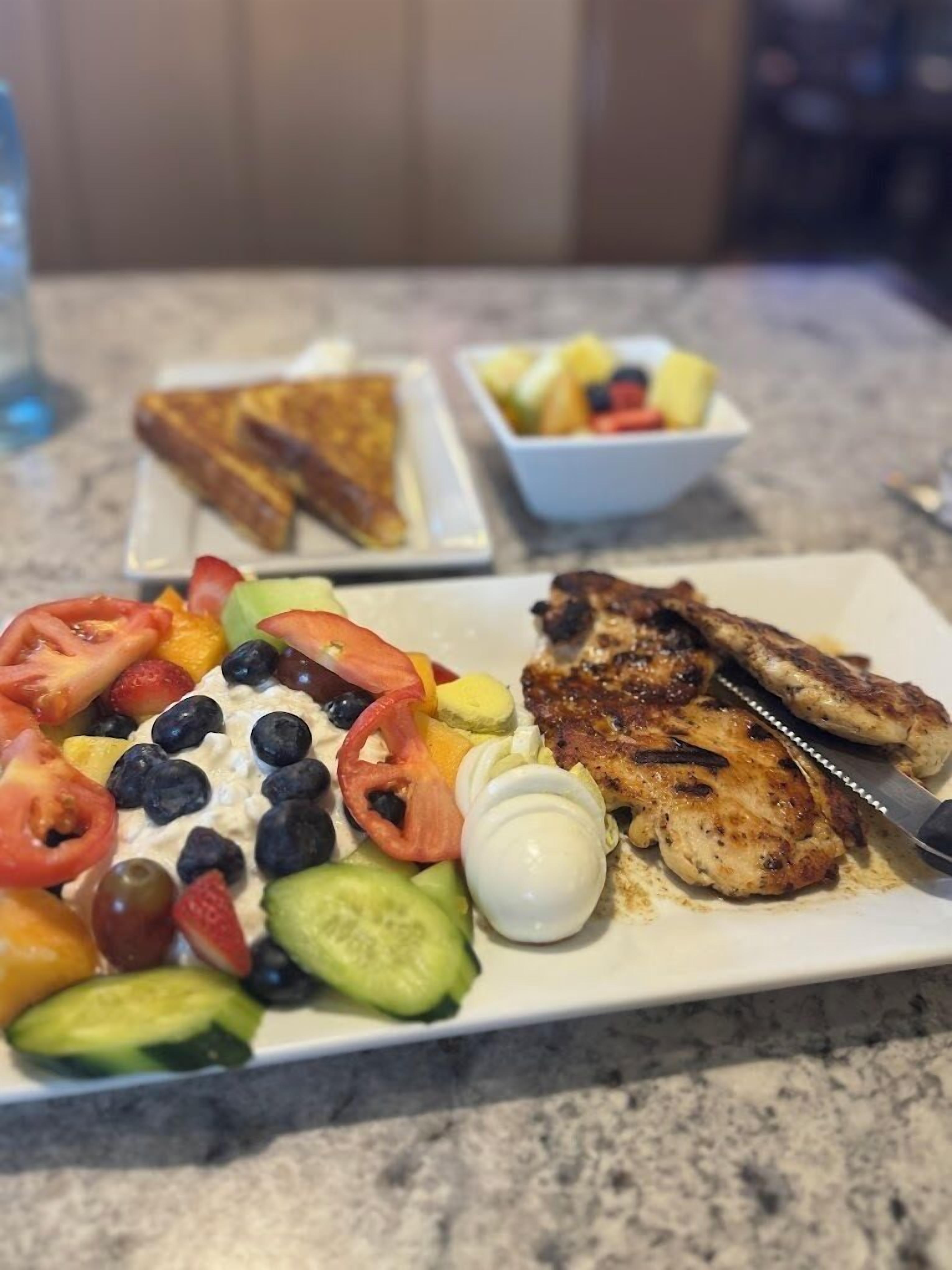 Un repas composé de poulet grillé, d’une salade et de pain grillé, servi sur une table.