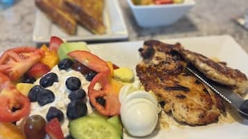 Un repas composé de poulet grillé, d’une salade et de pain grillé, servi sur une table.