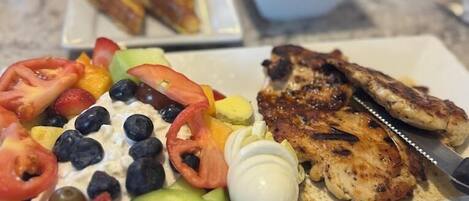 A meal with grilled chicken, a salad, and toast on a table.