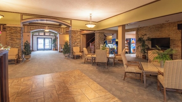 A spacious lobby with a stone fireplace, comfortable seating, a television, and a staircase leading to another level. - The Androy Hotel - Superior Duluth (Superior)