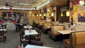 A restaurant with booths and tables, decorated for the holiday season with lights and snowflakes. - The Androy Hotel - Superior Duluth (Superior)