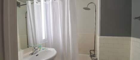 A bathroom with a white sink, mirror, and shower.