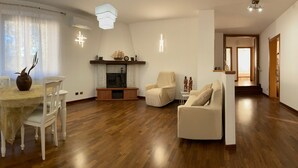 Una amplia sala de estar con piso de madera, un comedor con mesa y sillas, una chimenea y un sofá.