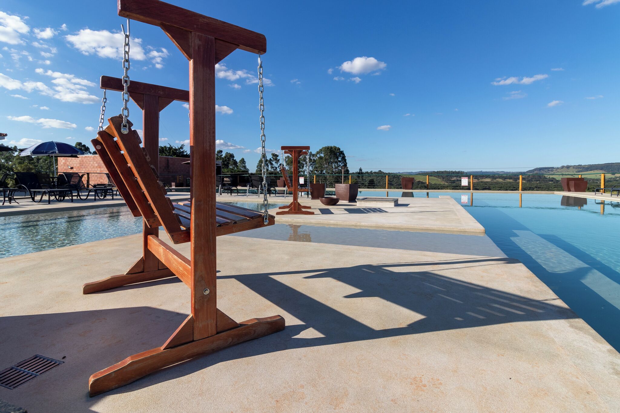 Una piscina al aire libre, sombrillas, sillones reclinables de piscina