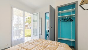 A bedroom with a bed, a sliding glass door leading to a balcony, and a blue closet with hangers.