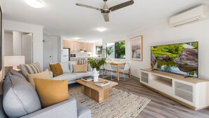 Un salon moderne comprenant un canapé, une table basse, un téléviseur et un coin repas.