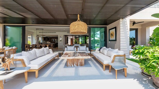A modern outdoor living area with a central coffee table, sofas, and a hanging light fixture.
